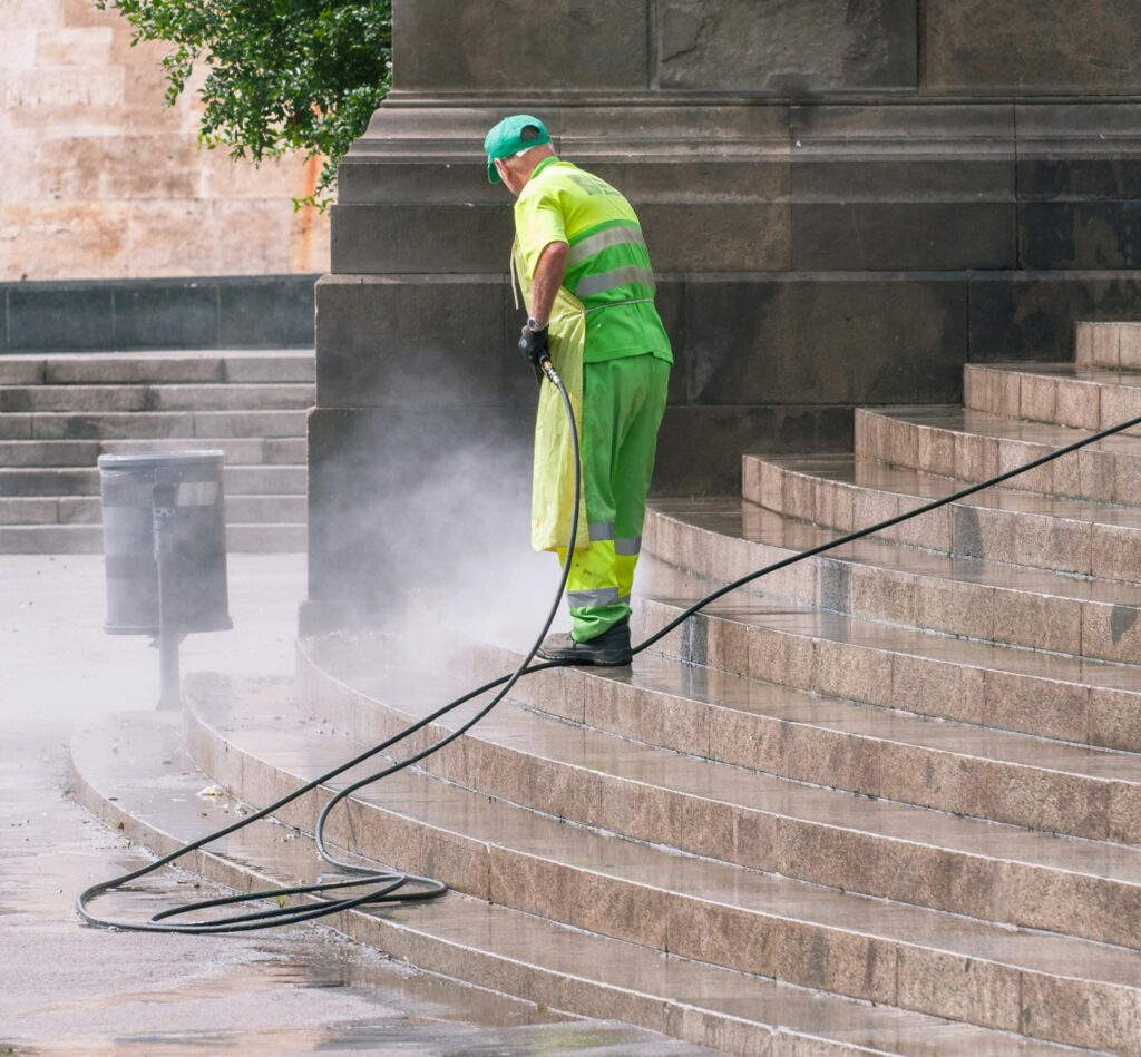A street worker pressure washes stone stairs in a public park, ensuring cleanliness and safety. service in Conroe Texas and Montgomery County